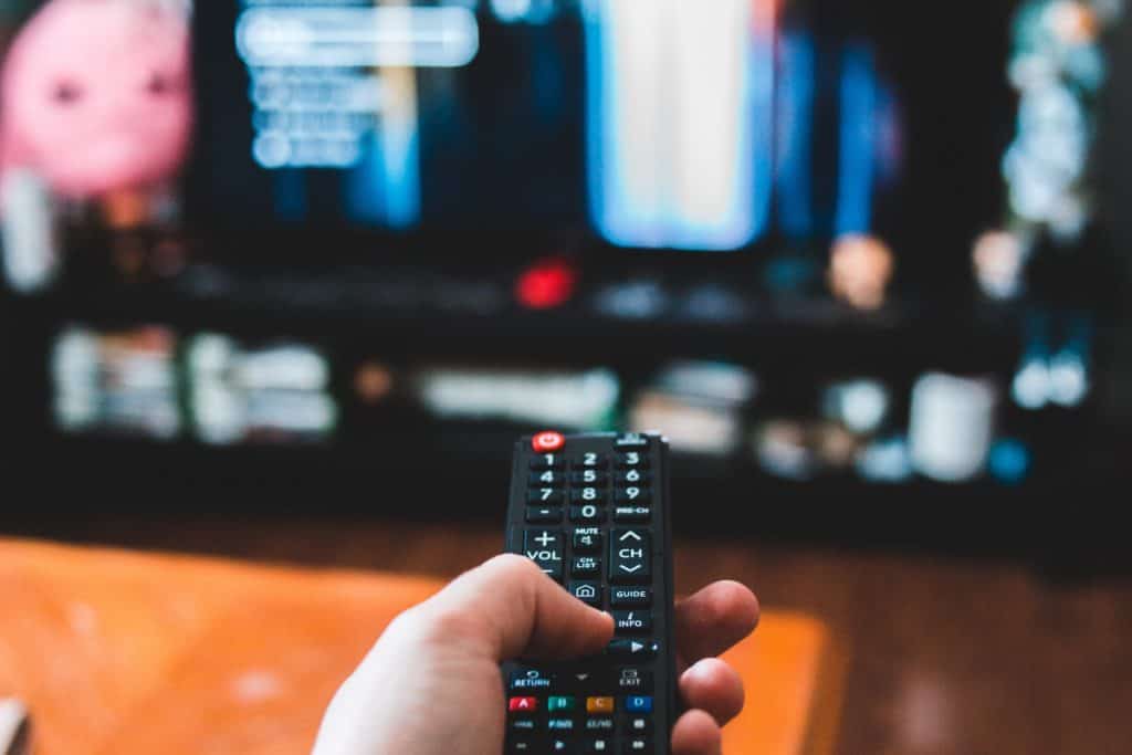 a person using tv remote controller to change channel